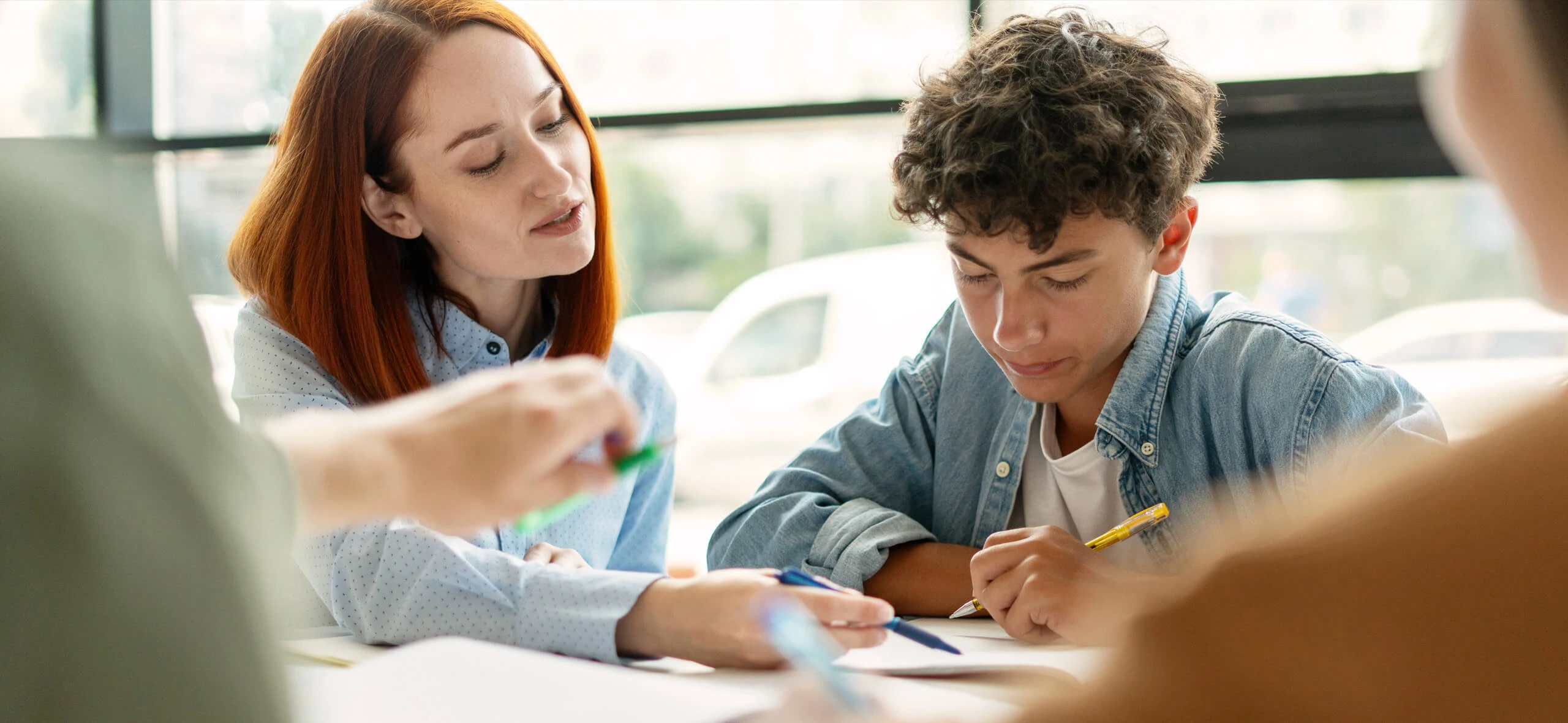 Eine Schulbegleiterin hilft einem jugendlichen bei Aufgaben.