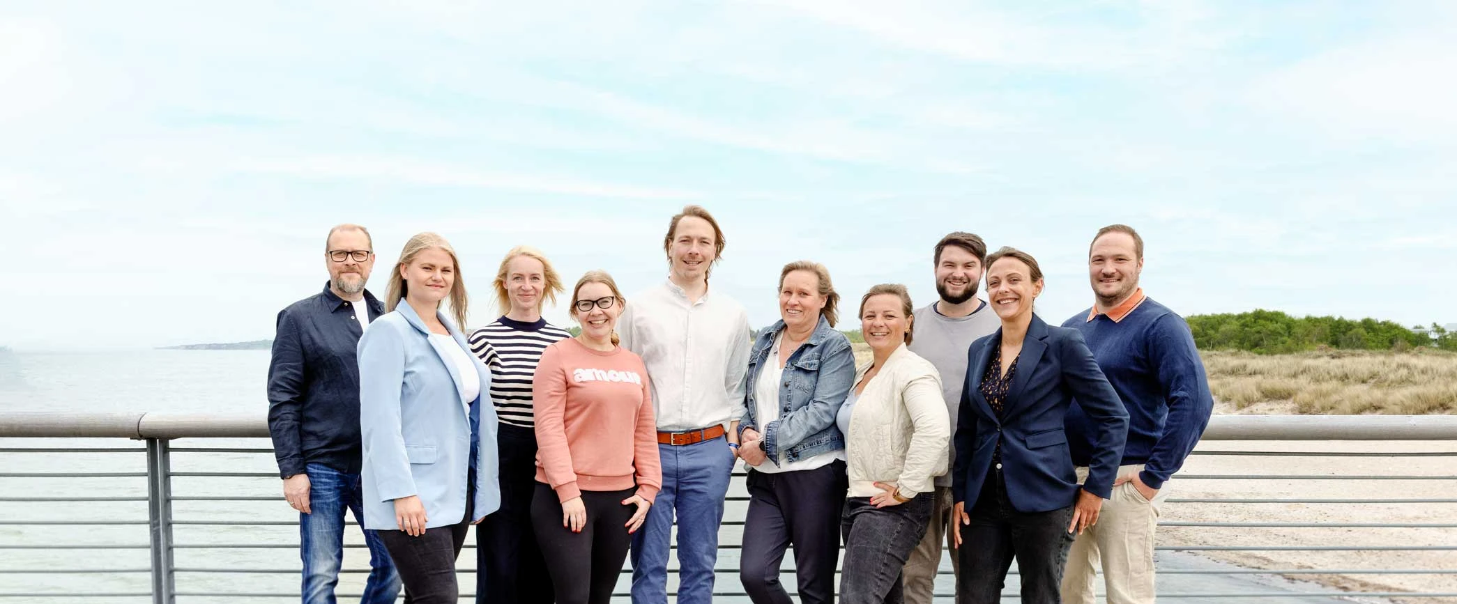 Gruppenfoto des Teams von Schulbegleitung Westküste auf einer Promenade am Strand.